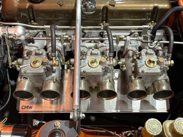 Close-up of classic car engine carburetors with metal intake manifold and fuel lines