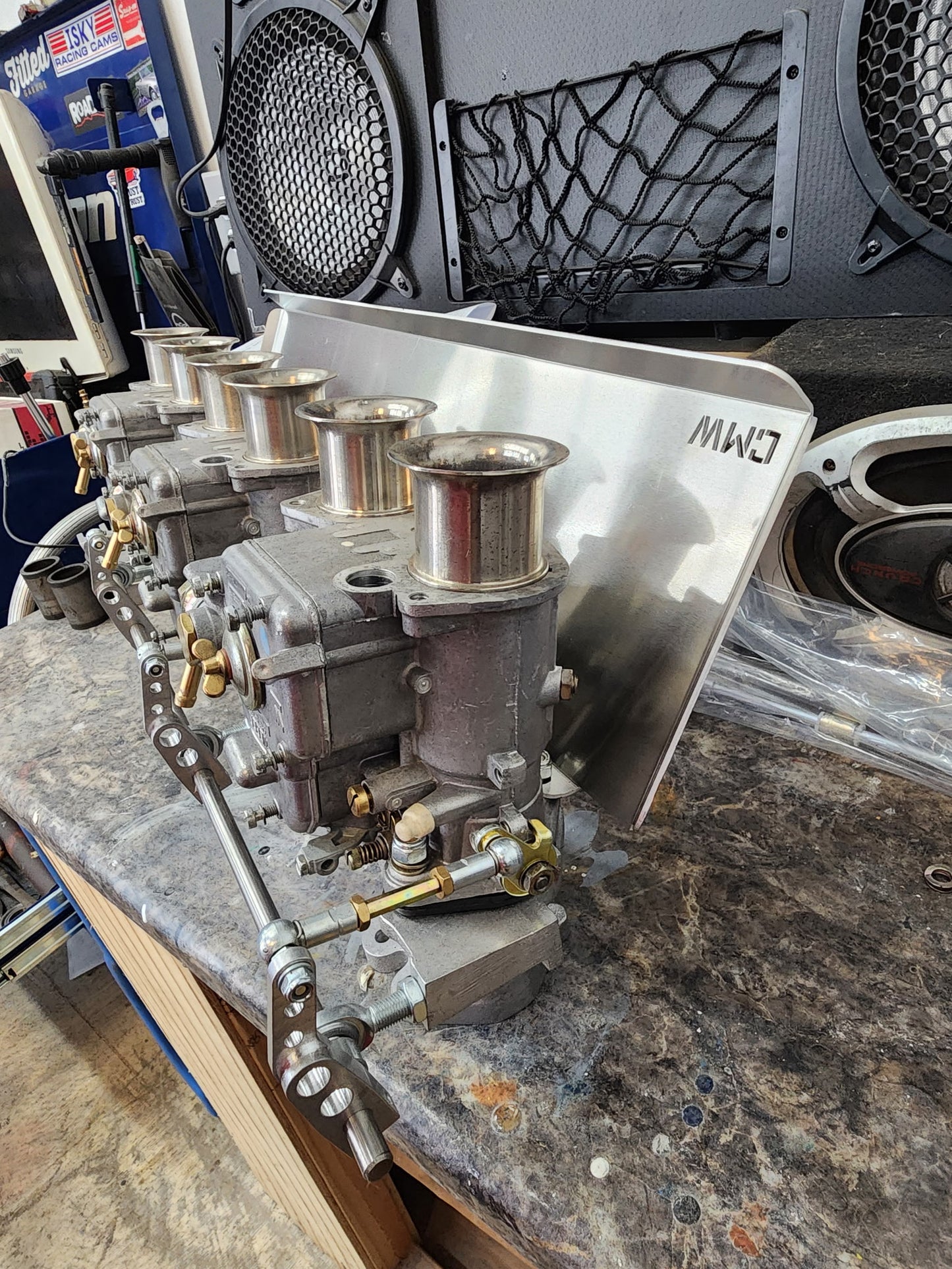 Performance carburetor assembly with intake trumpets on a workbench in an auto shop