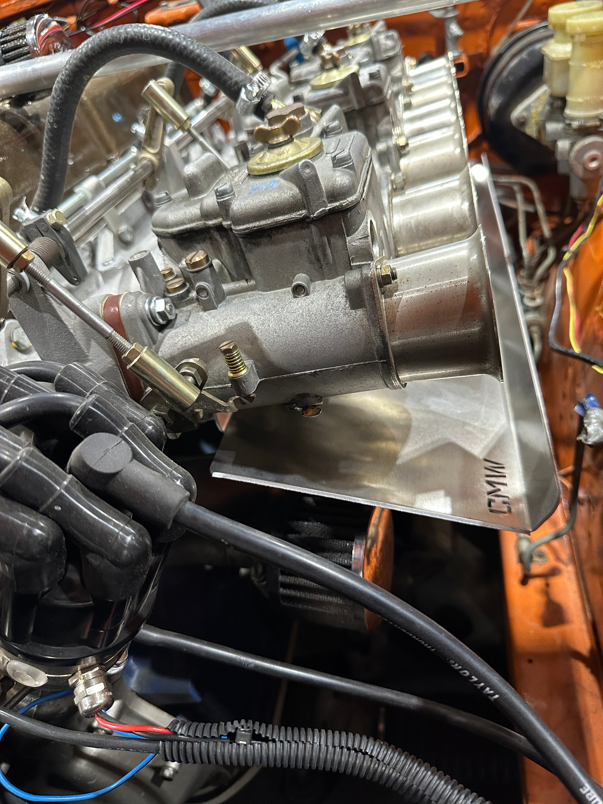 Close-up of classic car engine bay with carburetors, velocity stacks, and linkage details